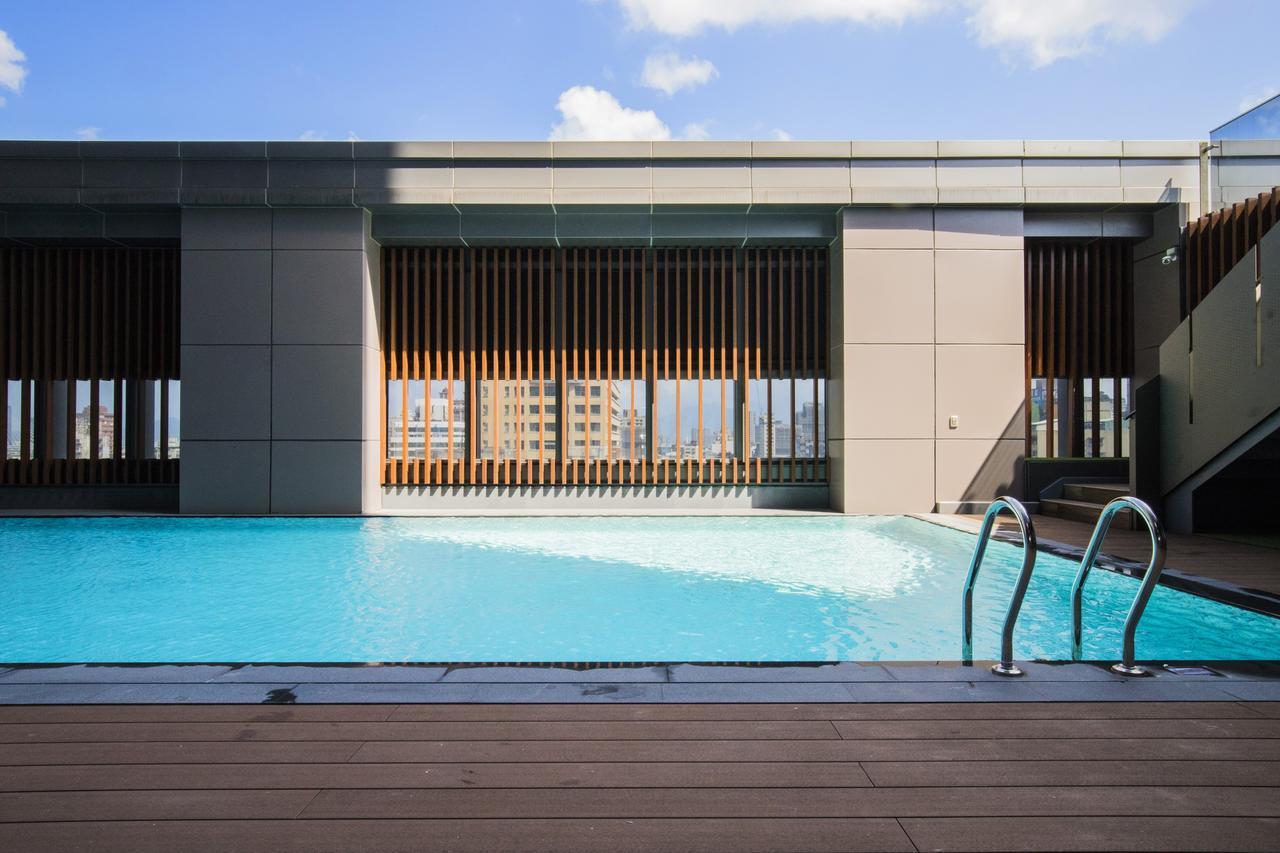 Caesar Metro Taipei Hotel Luaran gambar The photo depicts a modern rooftop swimming pool with clear blue water. The pool area is surrounded by a sleek, contemporary architectural design, featuring large windows and wooden slats that provide both an aesthetic appeal and some shade. In the b