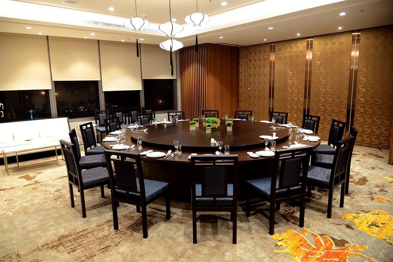 Caesar Metro Taipei Hotel Luaran gambar The photo shows a large, elegantly set dining room with a circular table surrounded by black chairs. The table is equipped with plates, utensils, and glassware, suggesting it's prepared for a formal meal. The room features modern lighting fixtures ha