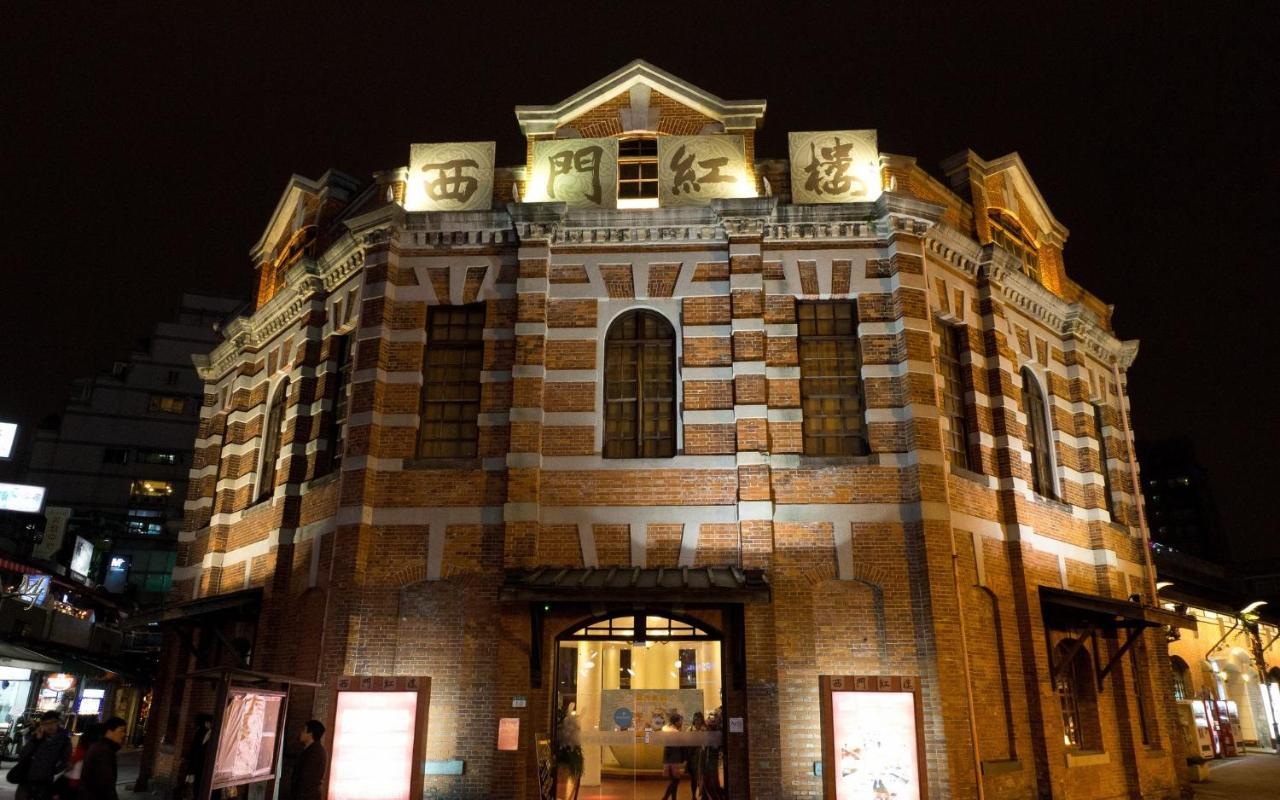 Caesar Metro Taipei Hotel Luaran gambar The photo shows a historical building illuminated at night. It features a distinct architectural style with a mix of brick and stone materials, characterized by a rounded structure and multiple windows. The front of the building is adorned with large